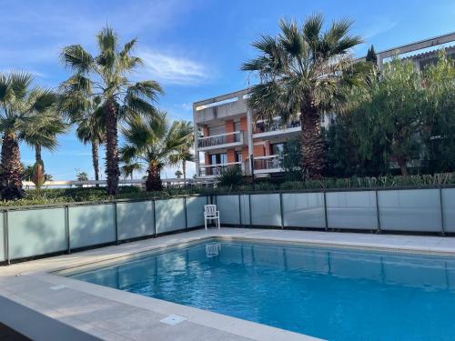 une piscine avec des palmiers et un bâtiment dans l'établissement VILLENEUVE LOUBET PLAGE- Entre NICE et CANNES, à Villeneuve-Loubet