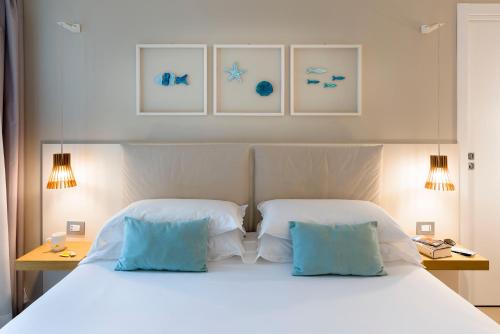 a bedroom with a white bed with two blue pillows at Albatros Beach Hotel in Letojanni