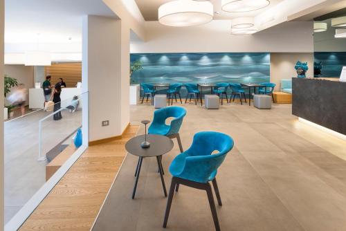 a waiting room with blue chairs and a table at Albatros Beach Hotel in Letojanni