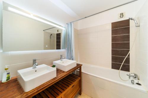 La salle de bains est pourvue de 2 lavabos, d'un miroir et d'une baignoire. dans l'établissement Le Valéria, à Saint-Denis