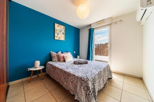 a blue bedroom with a bed and a window at Le Valéria in Saint-Denis