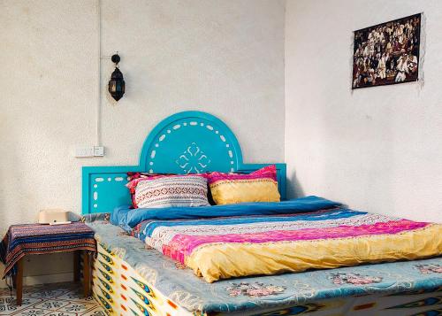 a bed with a blue headboard in a bedroom at New Dap Hostel (in Grape Town) in Turfan