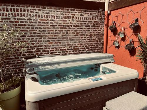 a pool of water in a bathtub in front of a brick wall at Studio indépendant et calme avec Jacuzzi à Lille in Lille