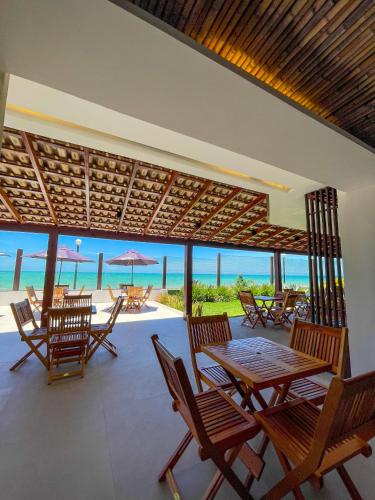 a patio with tables and chairs and the ocean at Hotel Vilarejo Praia in Rio das Ostras