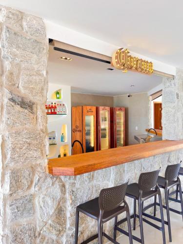 a bar with chairs and a stone wall at Hotel Vilarejo Praia in Rio das Ostras