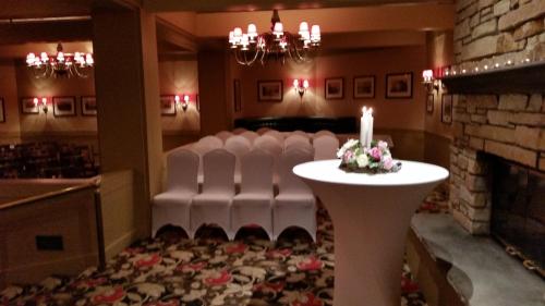 a room with white chairs and a table with a candle at Hotel Mead Resorts & Conventions Center in Wisconsin Rapids