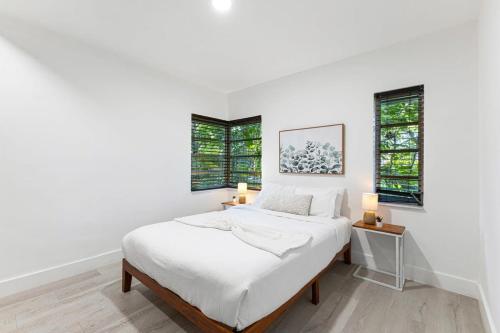 a white bedroom with a bed and two windows at Delight and cozy Apt close to Las Olas & the beach in Fort Lauderdale