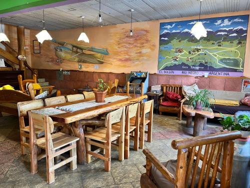 a restaurant with a large wooden table and chairs at Ankatu Hostel in El Bolsón