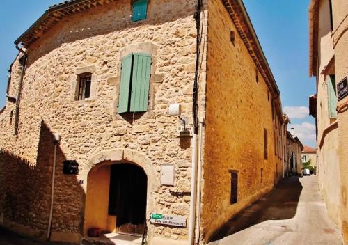 un vieux bâtiment en pierre avec une fenêtre verte sur une rue dans l'établissement Chambres d'hôtes & Spa privatif - Le Loft Gard, à Saint-Michel-d'Euzet