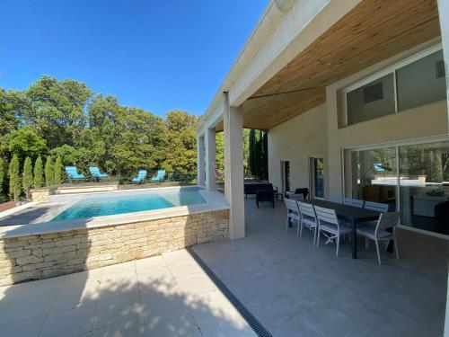 un patio avec une table et des chaises à côté d'une piscine dans l'établissement Grande Villa contemporaine à Grignan, à Grignan