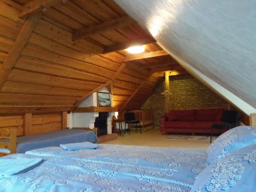 a attic room with a bed and a red couch at Dīva in Pāvilosta