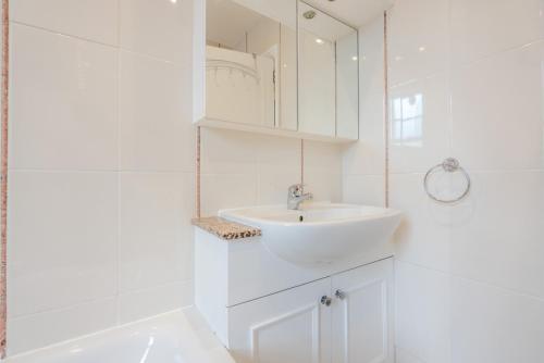 a white bathroom with a sink and a mirror at Hill Street Mayfair in London