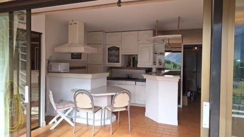 une cuisine avec des armoires blanches et une table et des chaises dans l'établissement Vue Exceptionnelle CASSIS, à Cassis