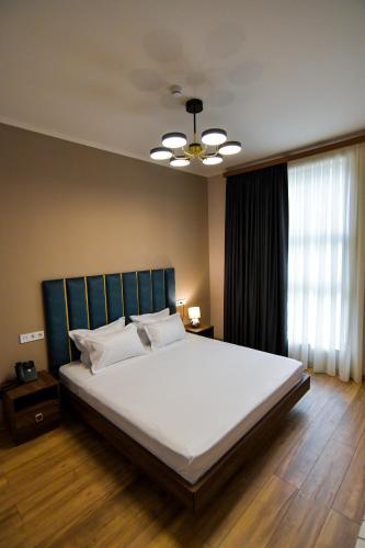 a bedroom with a large white bed with a ceiling at Gelati Residence in Kutaisi