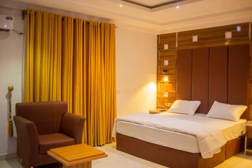 1 dormitorio con 1 cama y 1 silla en Jimaco Hotels and Suites, en Uyo