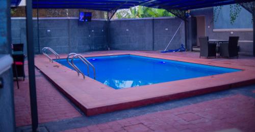 an empty swimming pool with an umbrella in a yard at Jimaco Hotels and Suites in Uyo