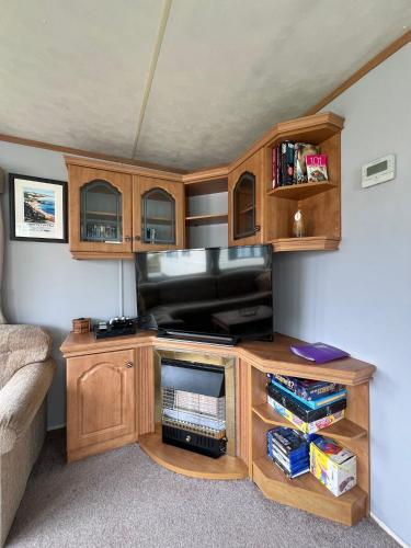 a living room with a entertainment center with a flat screen tv at Beautiful 2 bedroomed mobile home in Aberystwyth