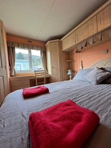 a bedroom with a large bed with red blankets on it at Beautiful 2 bedroomed mobile home in Aberystwyth