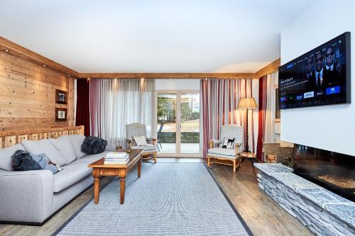 a living room with a couch and a tv at Route de Tsarbouye 17, 4BR, Les Dauphinelles in Crans-Montana