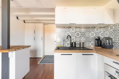 una cocina con armarios blancos y una pared de azulejos en charmant Studio mezzanine, en Biscarrosse