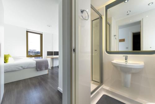 ein Bad mit einem Waschbecken und einem Spiegel in der Unterkunft Vibrant Byrom Point Retreat with Gym, Study Room and Social Lounge for Students Only in Liverpool