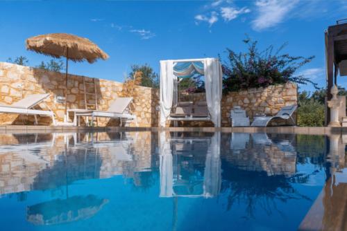 Villa Sar, a Cretan Private Retreat في Kambánion: مسبح مع كرسيين ومظلة