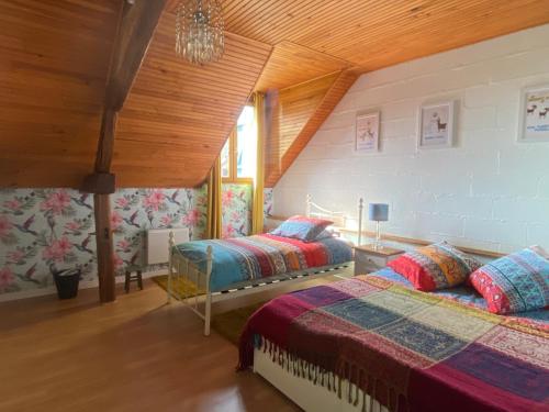 a bedroom with two beds and a wooden ceiling at Loire Valley Llama Farm Stay in Lavernat