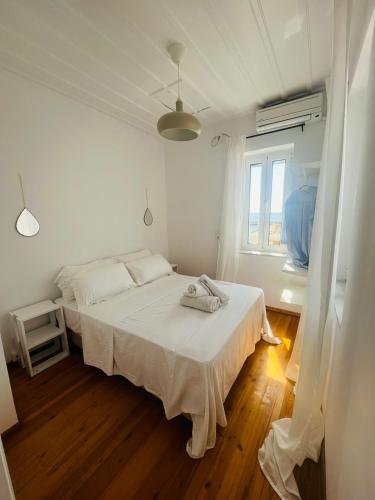 a white bedroom with a bed and a window at Green House - Central Stay in Plomari in Plomari