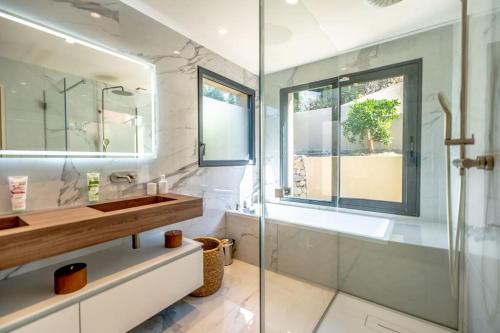 une salle de bain avec un lavabo et une douche en verre dans l'établissement Villa prestige avec piscine et sa vue mer au calme, à Grimaud
