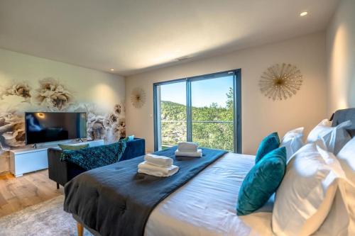 une chambre avec un grand lit avec une grande fenêtre dans l'établissement Villa prestige avec piscine et sa vue mer au calme, à Grimaud