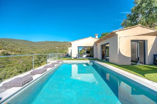 une piscine devant une maison dans l'établissement Villa prestige avec piscine et sa vue mer au calme, à Grimaud