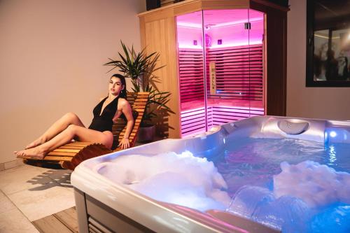 a woman sitting on a chair next to a hot tub at Espace évasions Loft Kis LOVE ROOM in Toulouse