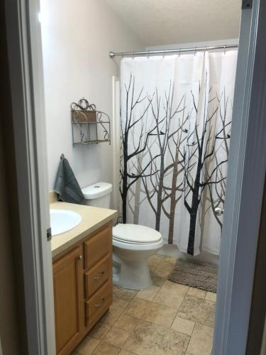 La salle de bains est pourvue de toilettes et d'un rideau de douche avec des arbres. dans l'établissement Summer Stop, à Eugene