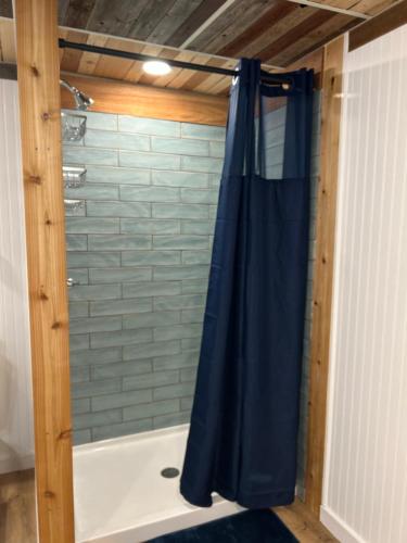 eine Dusche mit einem blauen Duschvorhang im Bad in der Unterkunft Border Queen Bunkhouse in Caldwell