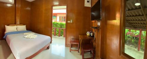 a bedroom with a bed and a table and a window at Ruen Nam Khoa Resort -Klongthom Krabi in Khlong Thom