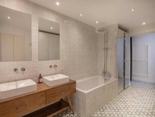 une salle de bain avec deux lavabos et une baignoire dans l'établissement Paris Center - Haussmann Elegant Residence, à Paris