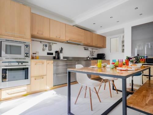 une cuisine avec des armoires en bois et une table avec des chaises dans l'établissement Paris Center - Haussmann Elegant Residence, à Paris