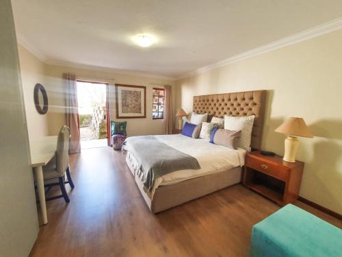 a bedroom with a large bed with a desk and a table at 2 Bedroom Self Catering Apartment in Waterkloofridge in Pretoria