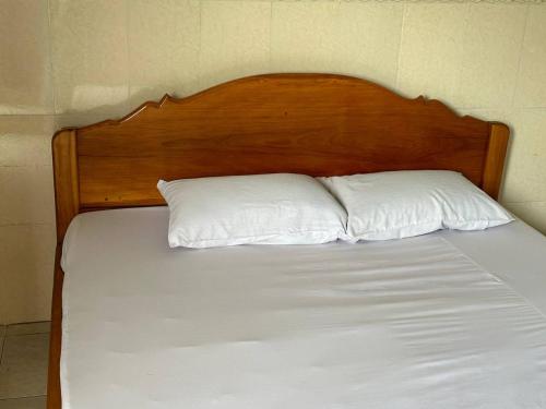 1 cama con cabecero de madera y 2 almohadas blancas en Palm Tree Quest House, en Battambang