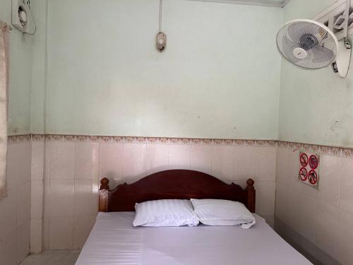 sypialnia z łóżkiem z 2 poduszkami i wentylatorem w obiekcie Palm Tree Quest House w mieście Battambang