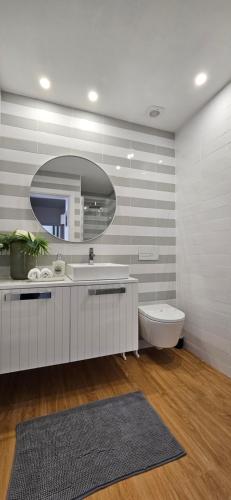 een badkamer met een wastafel, een toilet en een spiegel bij Casa "Patota" - Nazaré - Alojamento Local in Nazaré