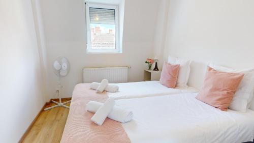 2 Betten in einem Zimmer mit weißen und rosa Kissen in der Unterkunft Appartements Rue du Chêne in Mulhouse