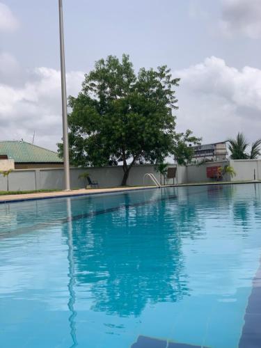 a large blue swimming pool with a tree in the background at PRIME LINE in Accra