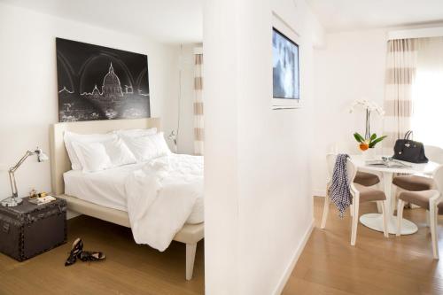 a white bedroom with a bed and a table at Via Del Corso Home Roma in Rome