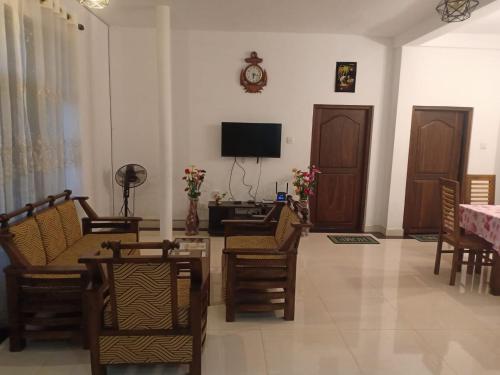 ein Wohnzimmer mit Stühlen und einem TV an der Wand in der Unterkunft Leyon-Tourist Inn in Negombo