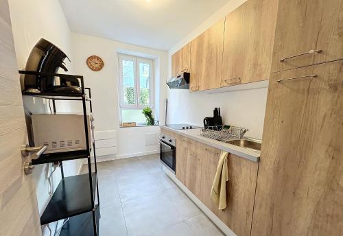 Elle comprend une petite cuisine avec des placards en bois et un évier. dans l'établissement Le K - Mulhouse Centre, à Mulhouse