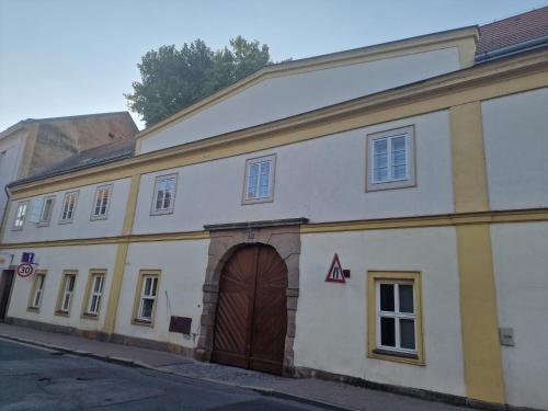 - un grand bâtiment blanc avec une porte marron dans l'établissement Apartmán Anežka 3 s vířivou vanou, à Jičín