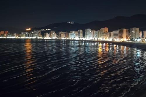 a view of a city at night from the water at Piso a 3 minutos de la playa!! 6 personas in Cullera