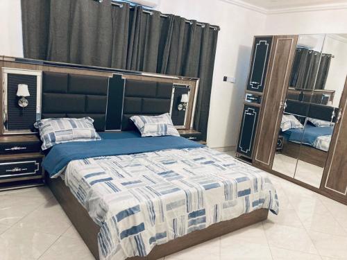 1 dormitorio con cama y espejo grande en The Peacock Mansion, en Kumasi