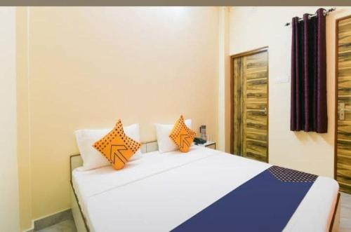 een slaapkamer met een wit bed met oranje kussens bij GRG Mahadeva Homes Guest House Prayagraj in Prayagraj